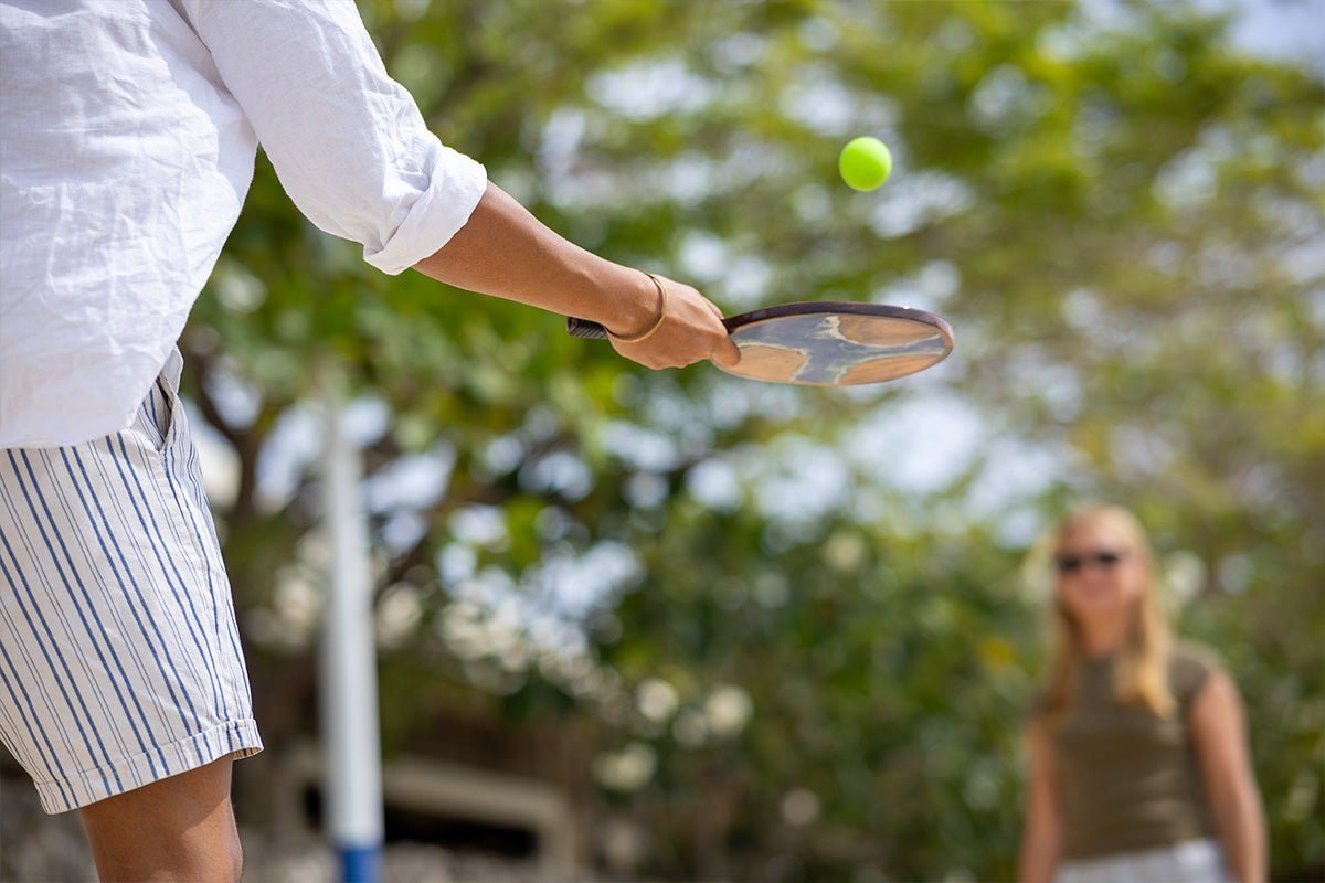 Two people playing paddle ball outdoors with Elakai wood paddles