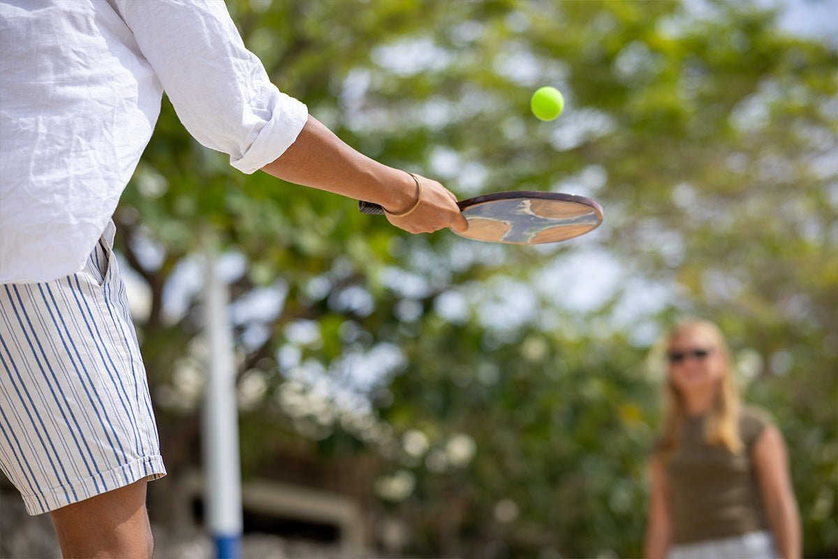 Two people playing paddle ball outdoors with Elakai wood paddles