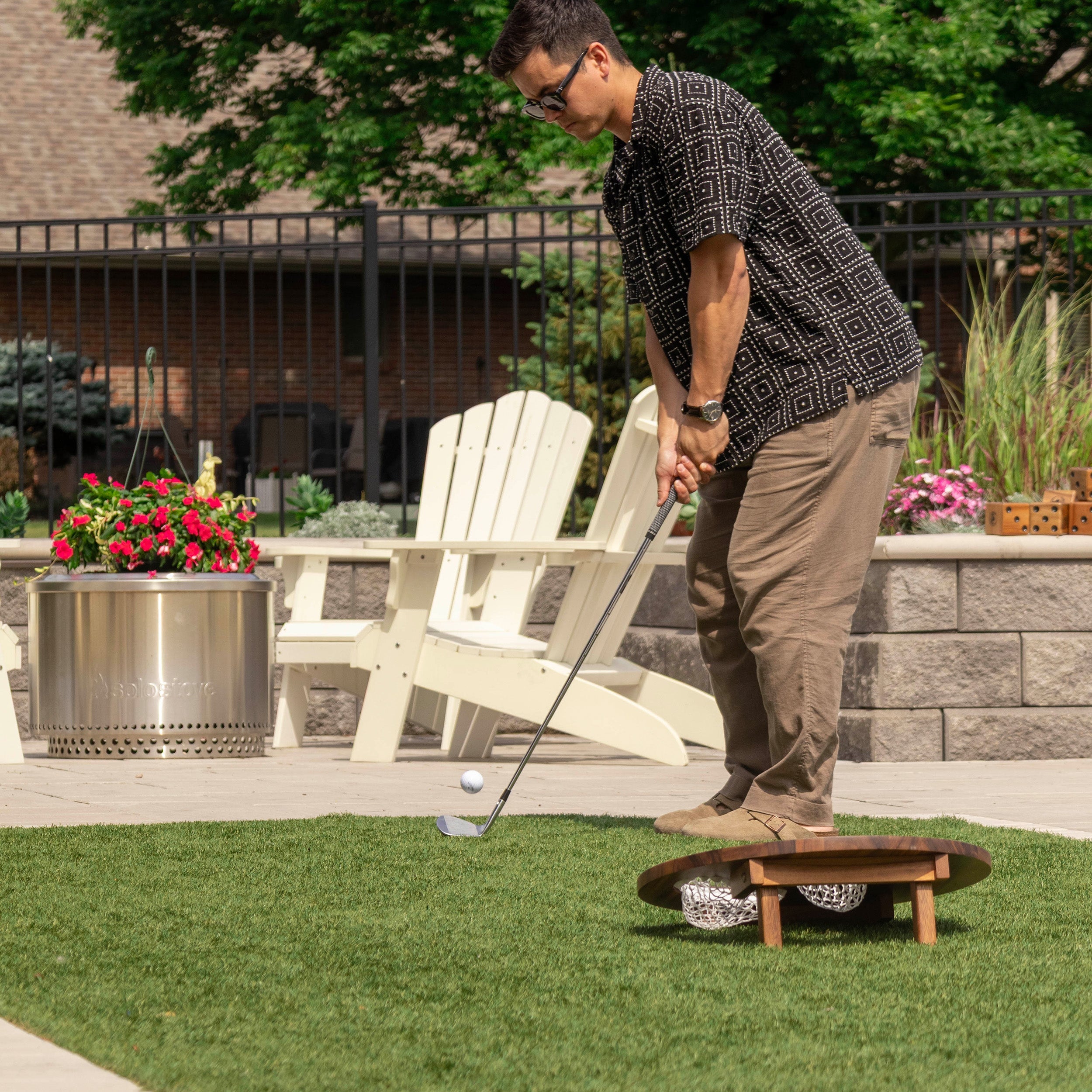 Person playing the Elakai Island Hole golf chipping game outdoors, chipping a golf ball toward the raised wooden target board