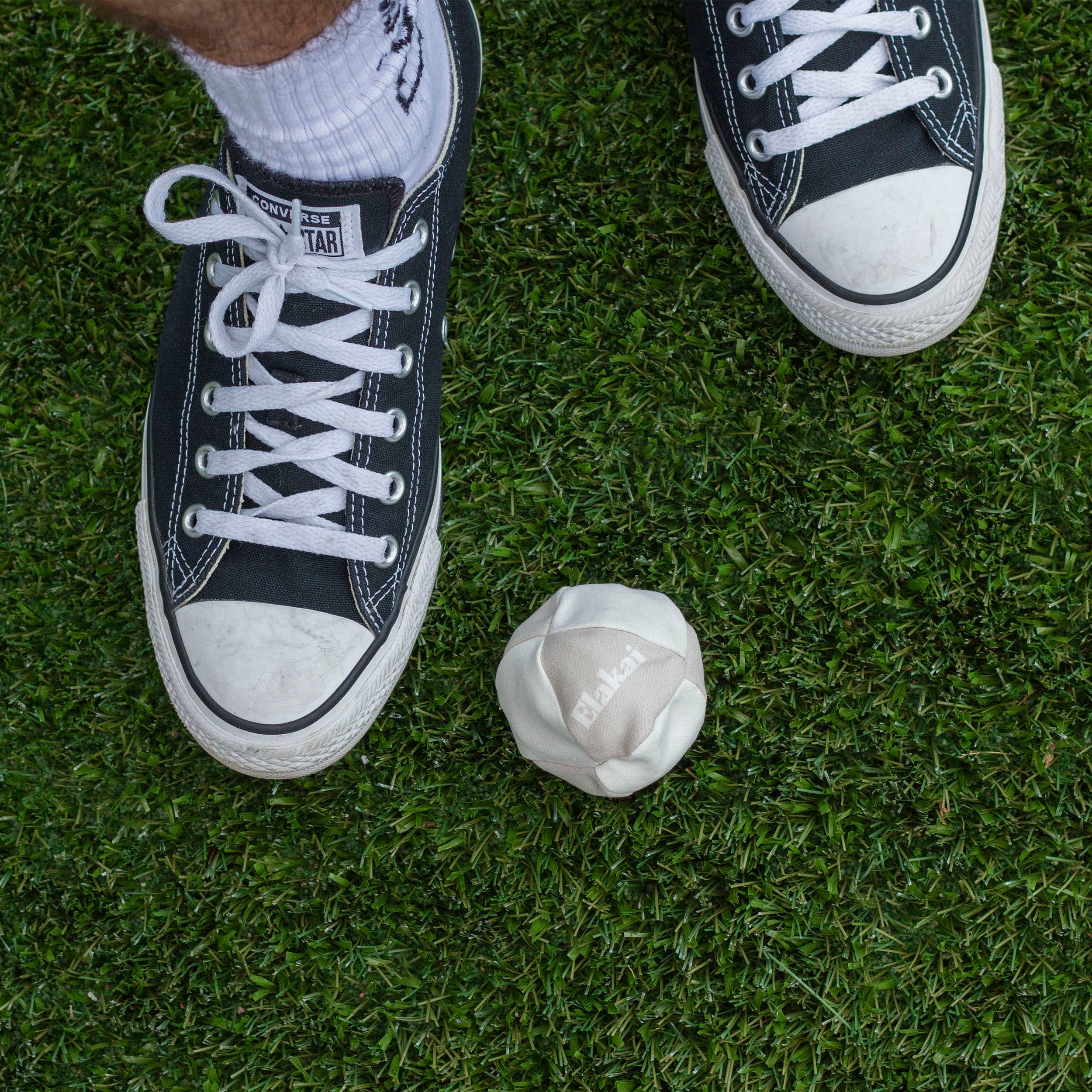 hacky sack in grass with converse shoes
#color_two tone neutral