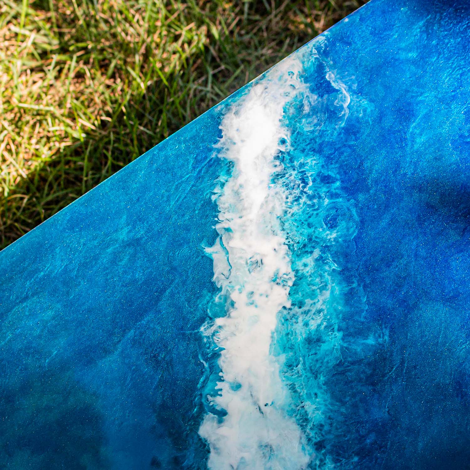 Macro detail of hand-poured resin wave and foam texture on cornhole board edge
