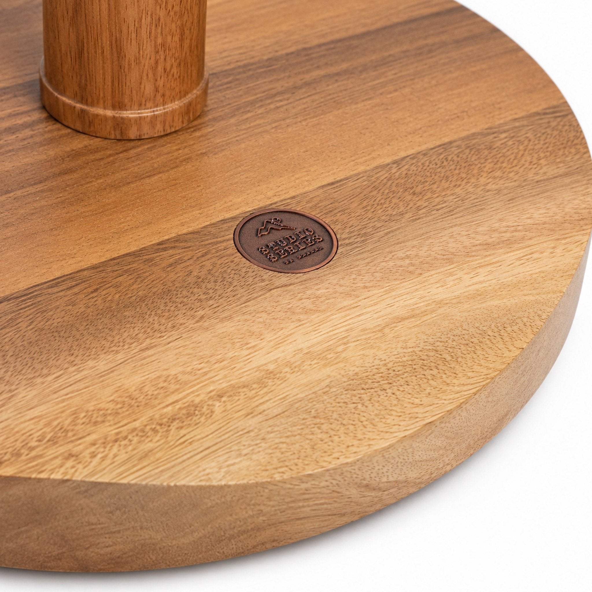 Close-up of the solid acacia base and stem of the Social Pong game, with the copper Studio Series medallion inlay