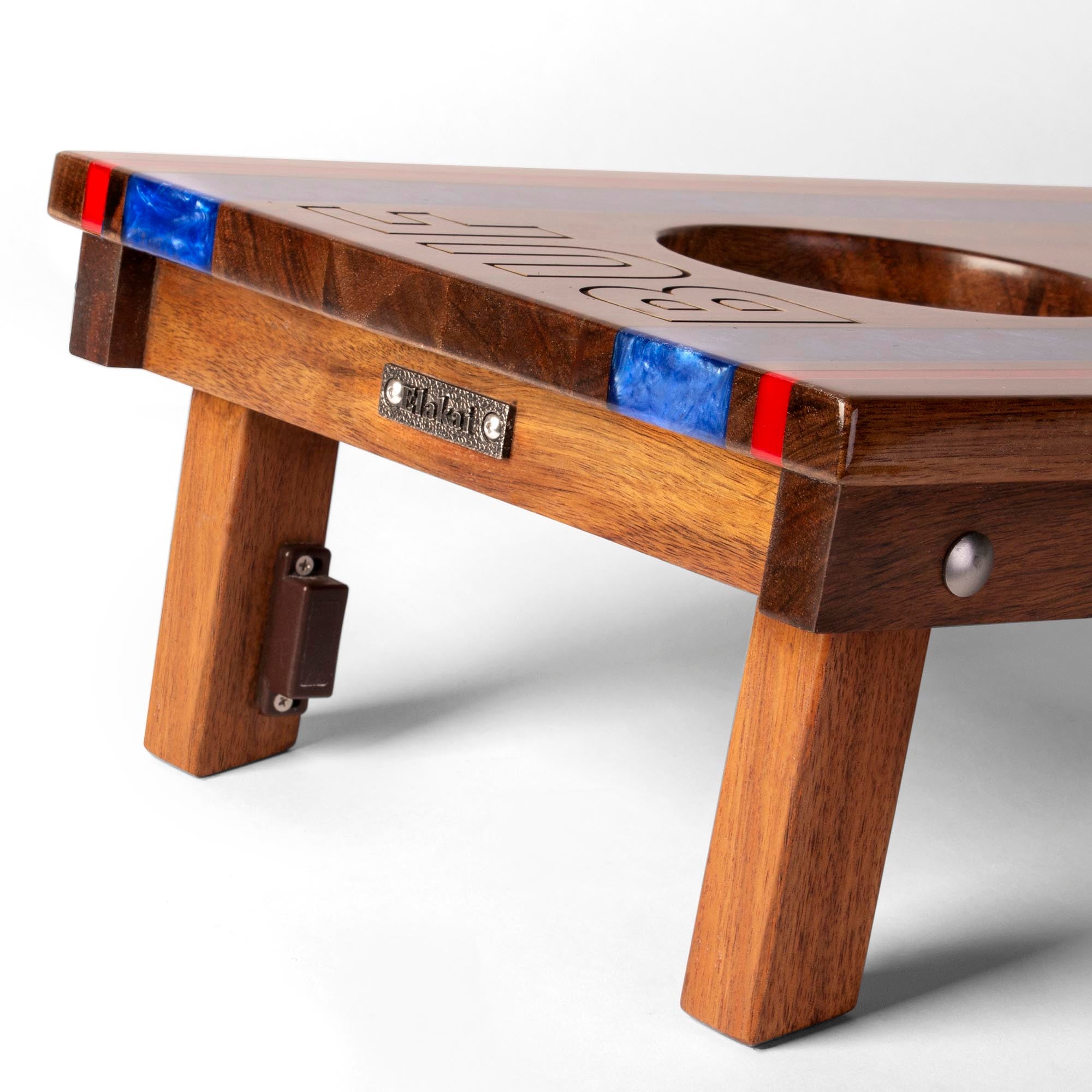 close-up detail of travel board with resin inlay, team engraving, folding legs, and metal Elakai badge 
#color_buffalo