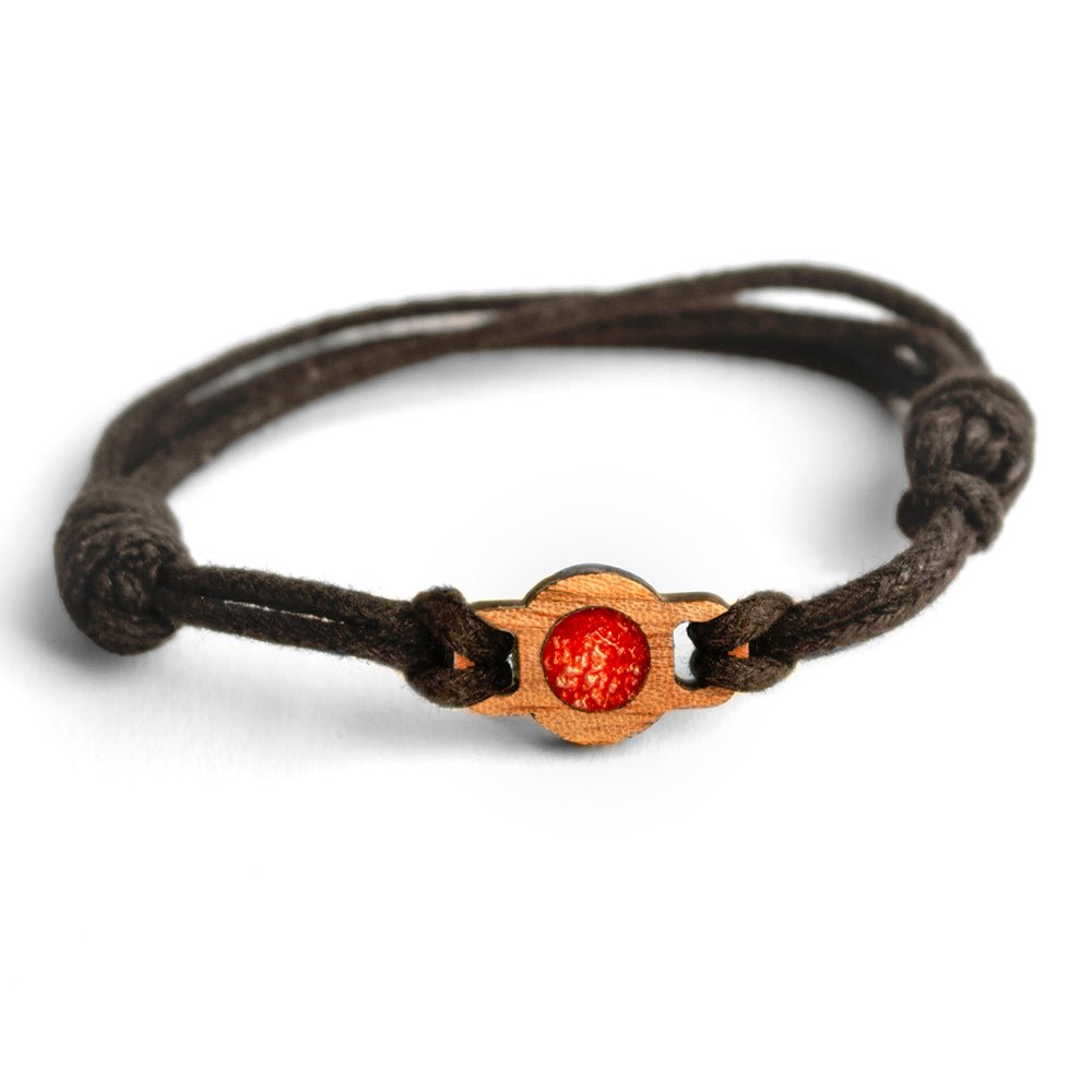 #color_metallic red swirl A brown metallic resin swirl bracelet with an adjustable waxed cord and a small wooden element with a red resin swirl in the center.