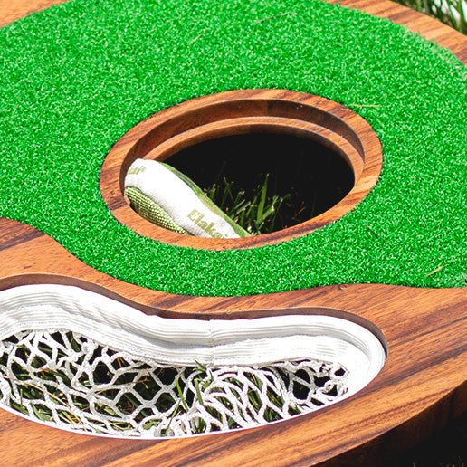 Close-up of a miniature golf hole with green grass and wooden border