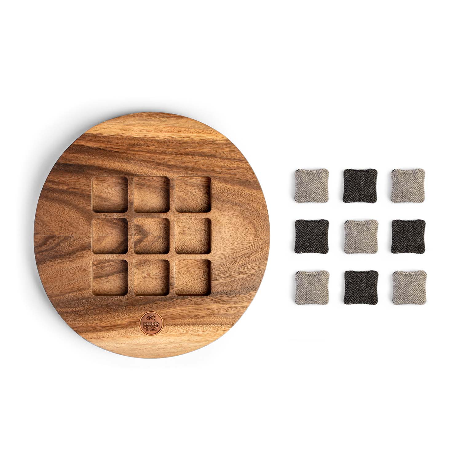 Flat lay of an acacia wood tic tac toe board with matching herringbone wool tic tac toe pieces arranged beside the board