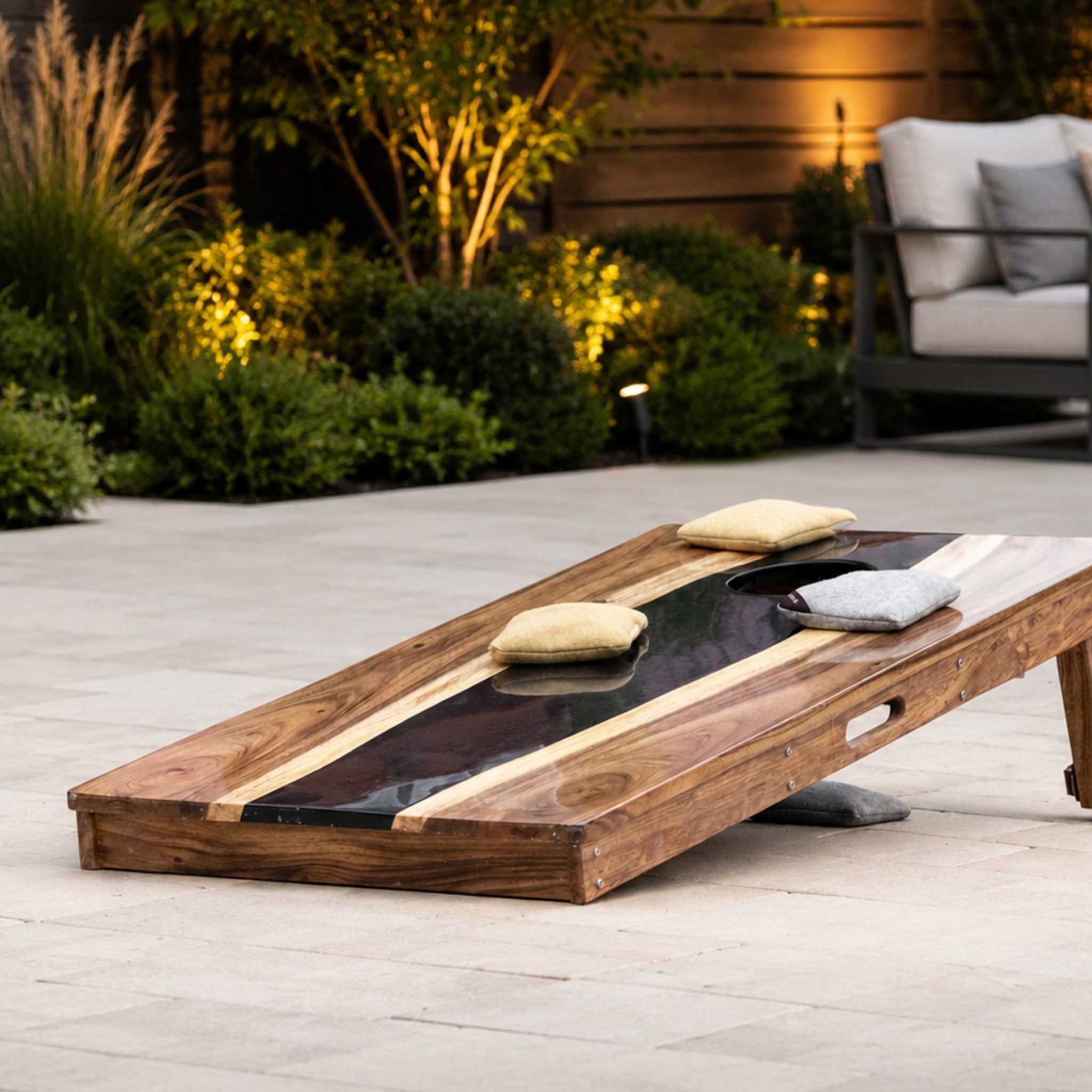 Resin river cornhole board in Black Pearl set up for game night on a patio #color_black