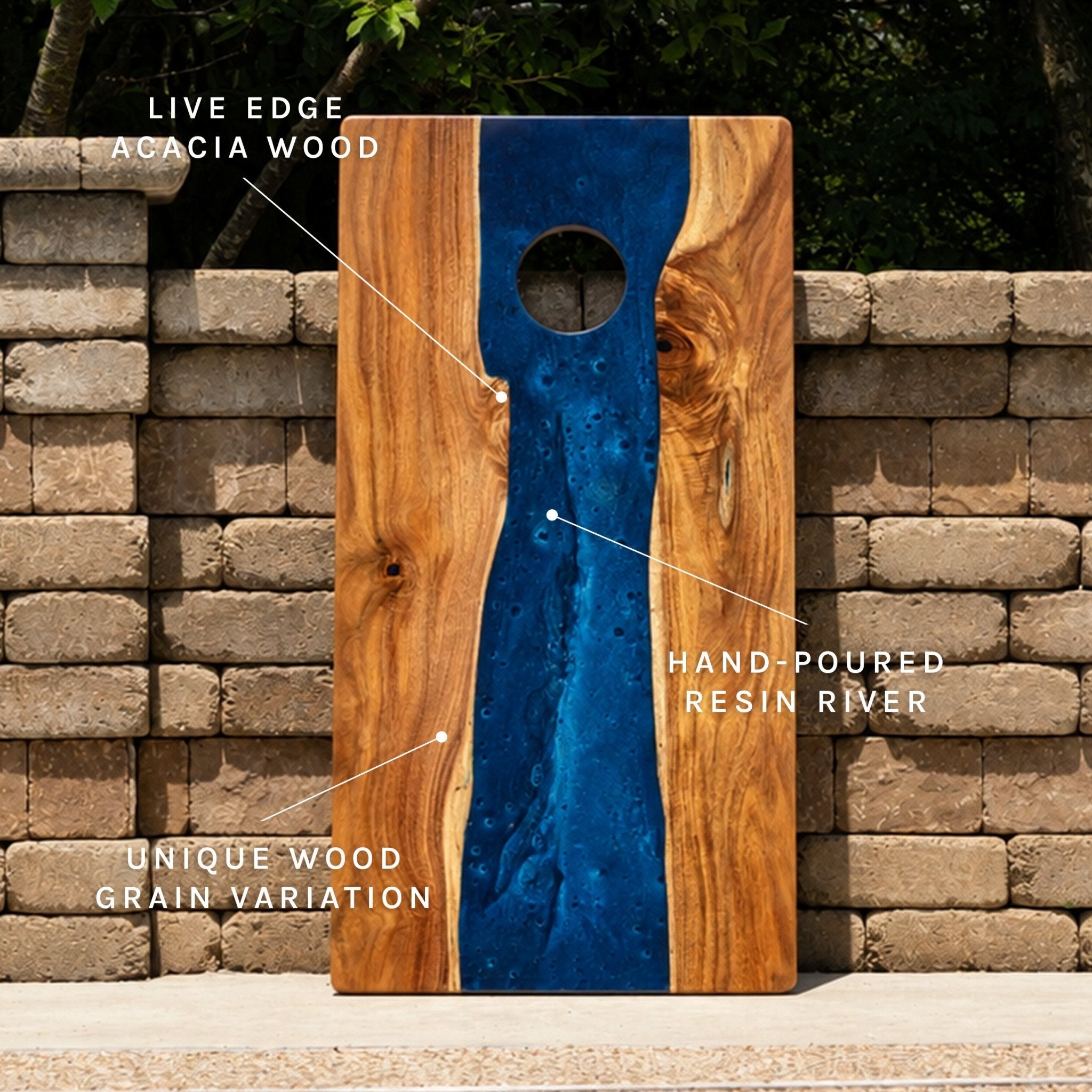 A wooden cornhole board with a live edge acacia wood border and a deep blue resin river down the center, shown outdoors against a brick wall with text callouts highlighting the materials. #color_blue pearl