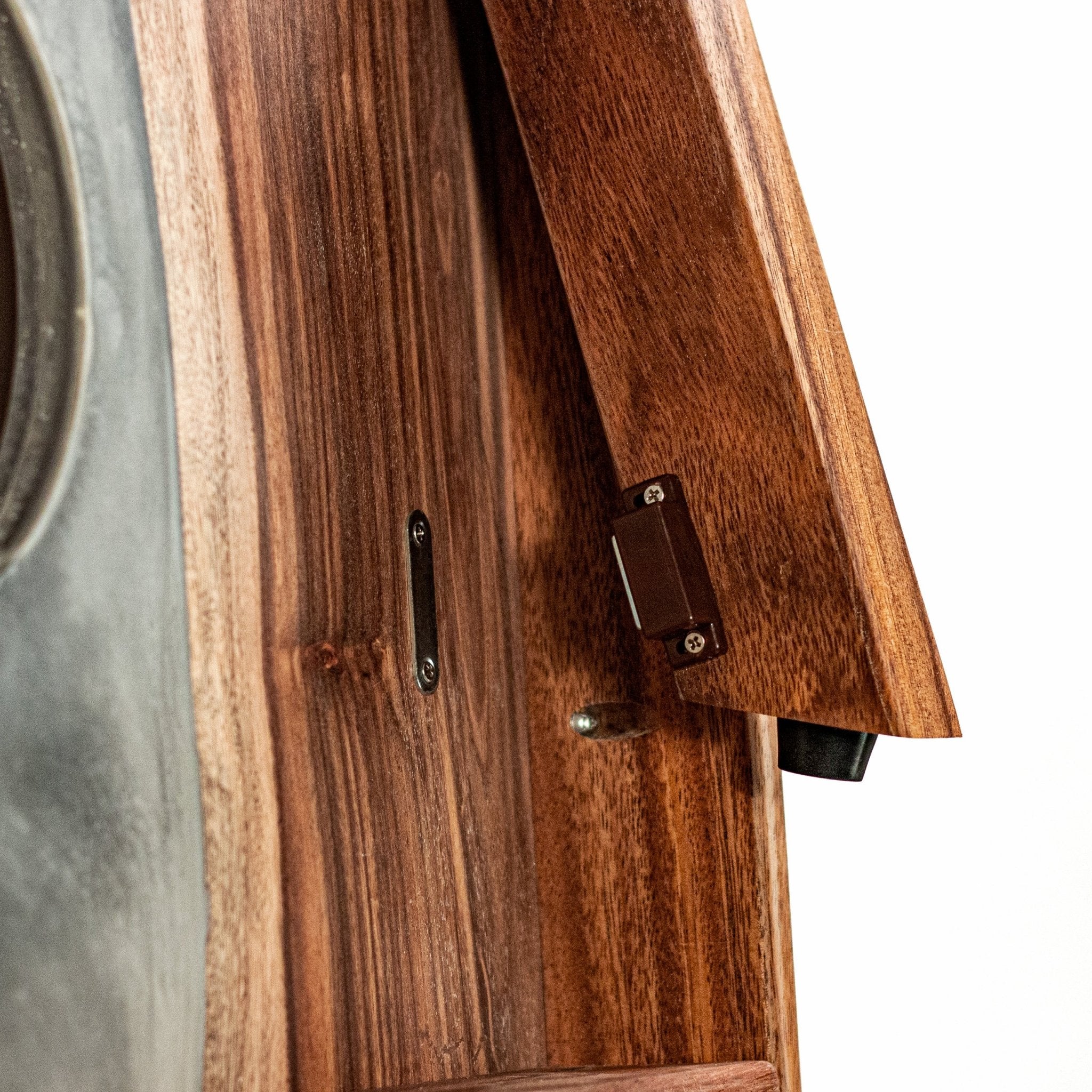 Close-up detail of a wooden cornhole board, dark metal hinges, and a textured gray surface on the left side, shown against a white background. #color_gray stone