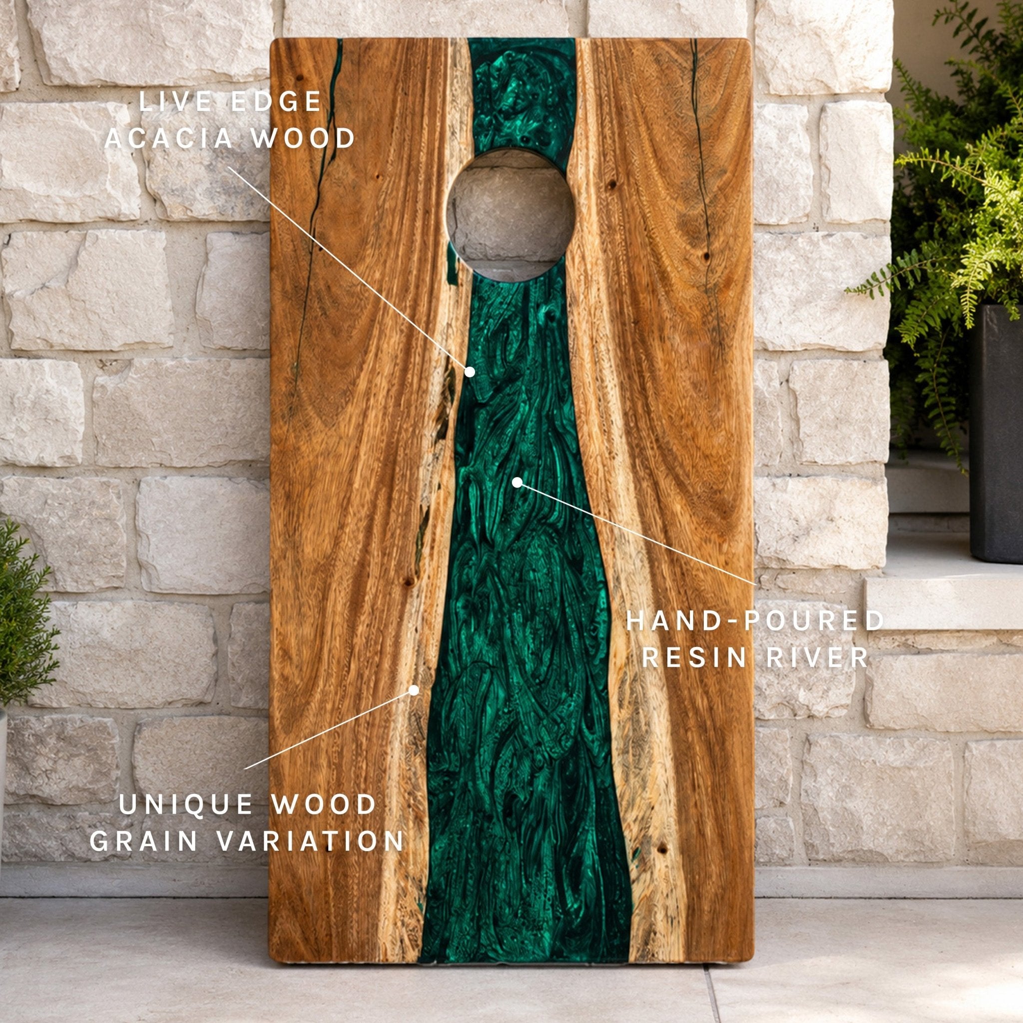 A vertical wooden cornhole board with a circular playing hole, featuring a natural brown wood edge and a vivid green hand-poured resin river down the center. White text callouts point to the liveledge acacia wood, the hand-poured resin river, and the unique wood grain variation, set against a stone wall background. #color_green pearl