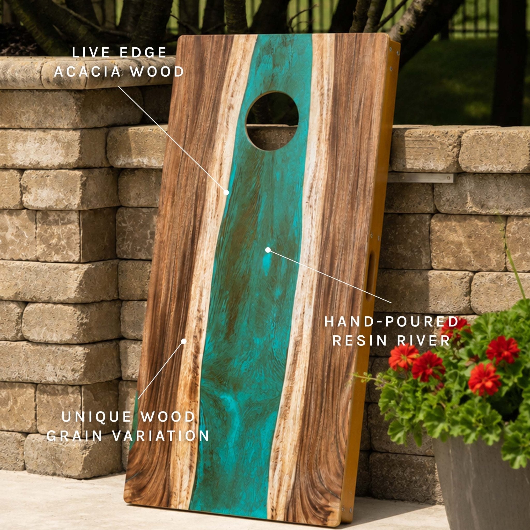 A cornhole board with a turquoise hand-poured resin river and live edge acacia wood, shown outdoors leaning against a stone wall with text callouts highlighting features. #color_teal and orange