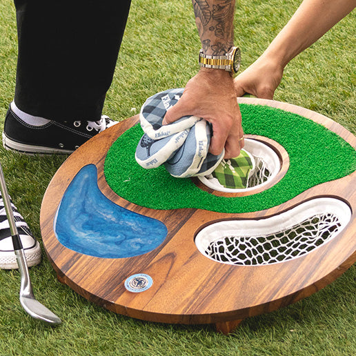 Person playing Island Hole mini golf on a wooden putting green with grass background